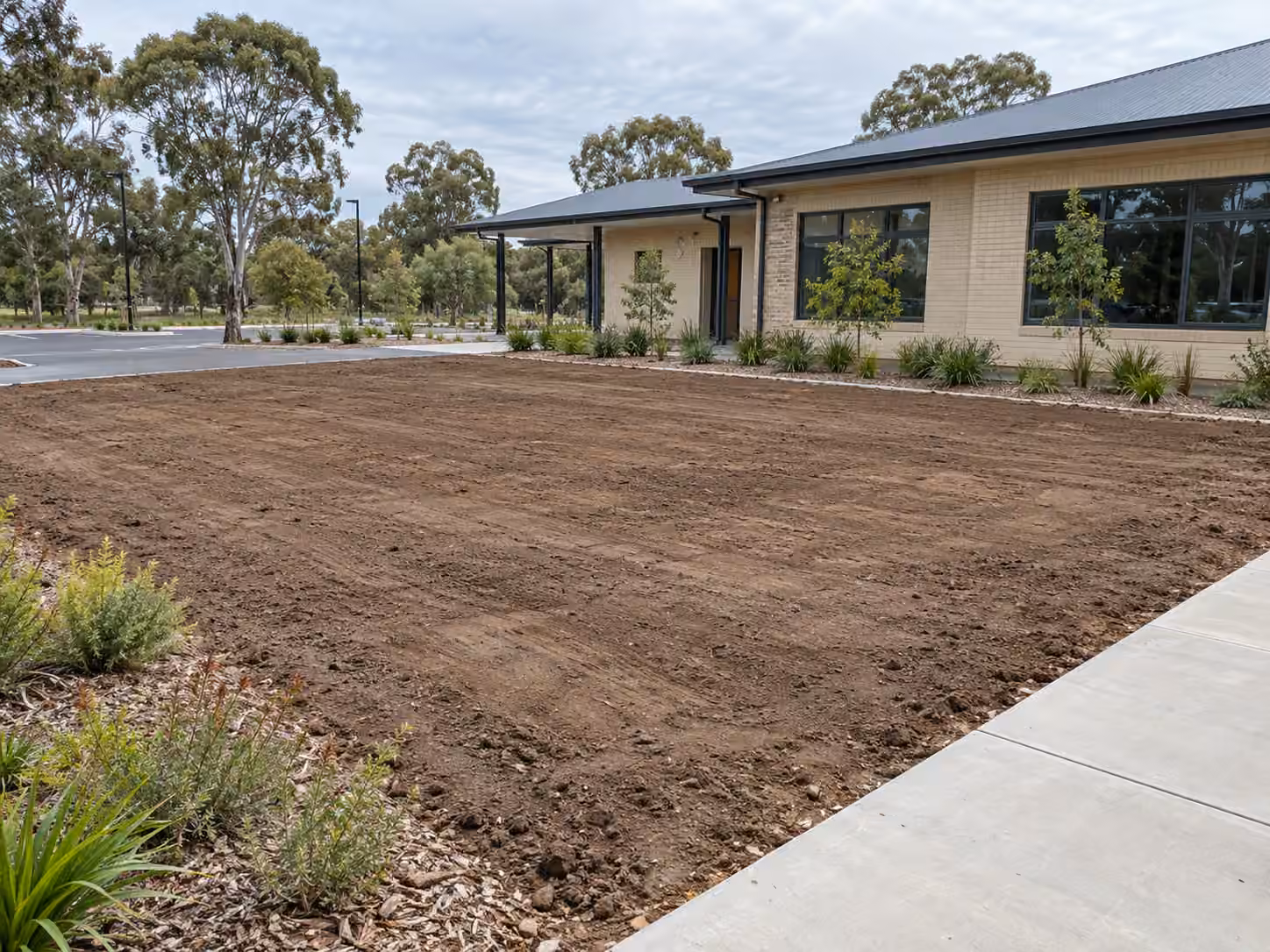 Prepared ground beside a commercial facility before turf installation