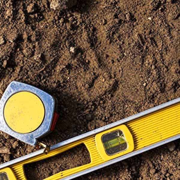 Spirit level and tape measure on prepared soil